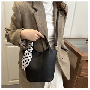 Detail of black pebbled leather bucket bag with decorative polka dot silk scarf handle