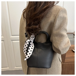 Detail of black lychee grain bucket bag with polka dot scarf on wool coat