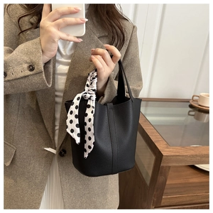 Detail of black pebbled leather bucket bag with decorative polka dot silk scarf handle