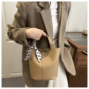 Litchi texture leather bucket bag with polka dot scarf detail held by model