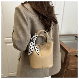 Detailed view of camel bucket bag with lychee grain leather and decorative silk scarf