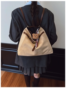 Dettaglio di una grande borsa tote beige scamosciata con ciondolo a orsetto sulla spalla