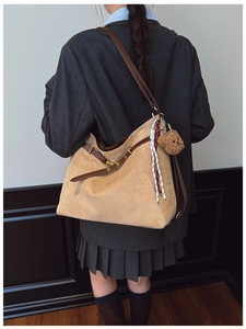 Detail of light brown suede tote bag with cute bear charm and vintage strap hardware