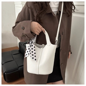 Détail du sac seau en cuir litchi blanc avec poignée décorée d'un foulard à pois