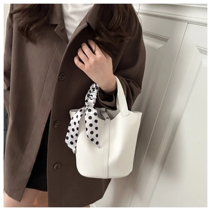 Close-up of white lychee textured bucket bag with a stylish polka dot scarf on handle