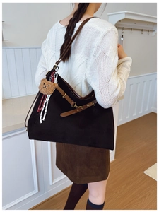 Dettaglio di una borsa tote color caffè scuro indossata con maglione bianco e gonna