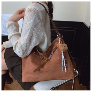 Borsa tote in camoscio marrone con spalline in pelle e ciondolo a orsetto su modella