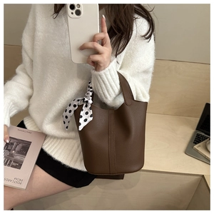 Détail du sac seau en cuir marron foncé avec foulard décoratif en soie à pois