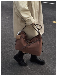 Close-up of brown suede tote bag featuring leather straps and a plush bear pendant charm