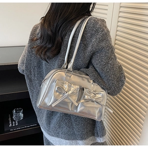 Detail view of silver metallic shoulder bag with bow pockets and glossy leather finish