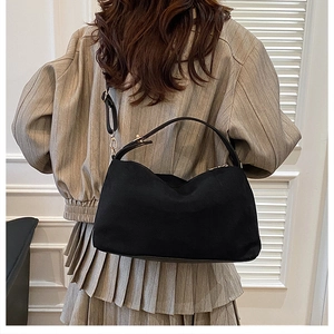 Detailed back view of a black suede hobo bag shown on a model for size perspective