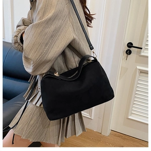 Modern black matte shoulder bag styled with a gray jacket and pleated skirt for daily wear