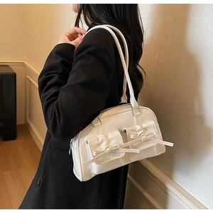 Detail view of ballet style cream shoulder bag with stylish bow pockets on a model