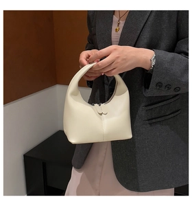 Detail of minimalist cream half-moon handbag showing soft leather texture and zipper close-up