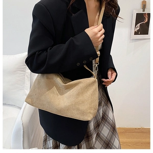 Detail of suede crossbody bag with fine shoulder strap and golden metal buckles