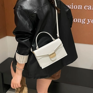 Sac à bandoulière chic en simili cuir blanc avec boucle dorée porté par un mannequin en cuir