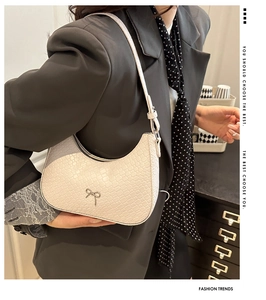 Détail du sac baguette minimaliste en texture crocodile crème avec nœud argenté