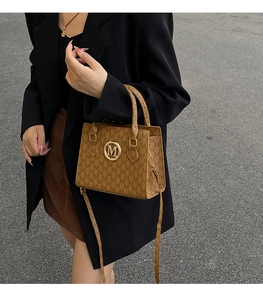 Dettaglio della borsa monogramma marrone con fibbia M dorata e tessuto jacquard operato