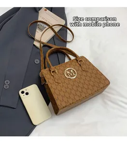 Borsa tote marrone monogram con logo M mostrata in scala con uno smartphone