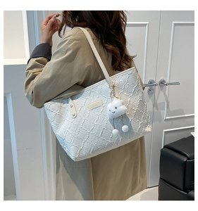 Detail of white jacquard tote bag with plush cloud charm worn by a model
