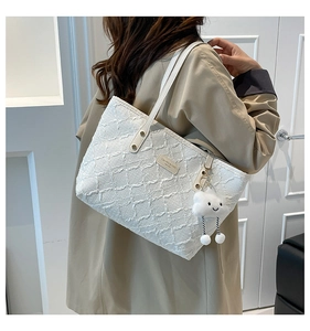 Detail of white textured tote bag with fluffy cloud charm and metal brand plate