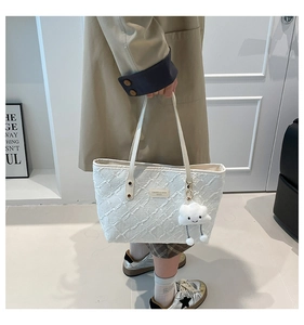 Detail of white textured tote bag featuring quilted pattern and cute plush cloud charm