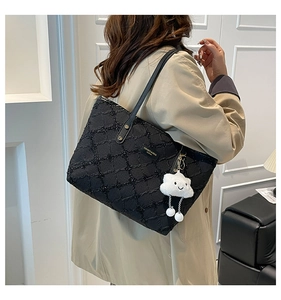 Detail of quilted tote bag with sequins and cloud pendant worn by a model