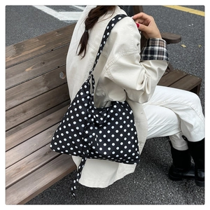 Classic black and white polka dot tote bag styled in a casual outdoor setting