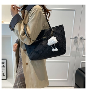 Close-up of black quilted tote bag with sequins and a white plush cloud charm