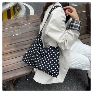 Grand sac fourre-tout à pois porté à l'épaule dans un décor extérieur naturel et élégant