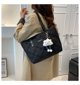 Close-up of quilted black tote bag with slim leather strap and white cloud charm accessory
