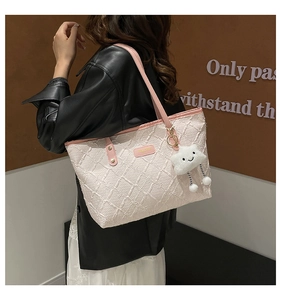 Detail of light pink quilted tote bag featuring a plush cloud charm and leather handle