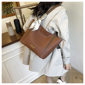 Détail du sac cabas marron avec foulard décoratif et inscription dorée sur le cuir