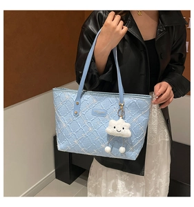 Light blue tote bag with embossed texture, bow detail and cloud plush charm shown on model