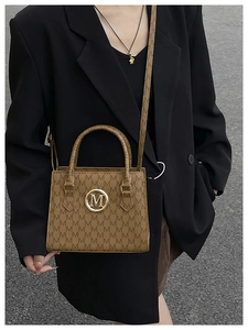 Detail of brown monogram shoulder bag with gold M-logo buckle and structured short handle