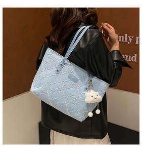 Detail of light blue bohemian tote bag with textured patterns and cloud charm accessory