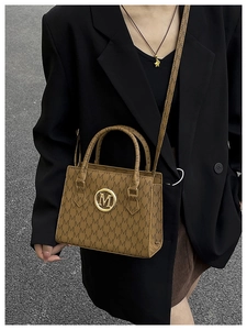 Straßenstil-Ansicht einer Frau im schwarzen Blazer mit brauner Monogramm-Handtasche