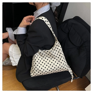 Polka dot hobo bag with half-moon shape worn by model in a stylish street setting
