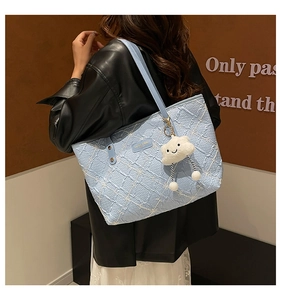 Detail of light blue floral embossed tote bag with cute cloud charm and metal logo plate
