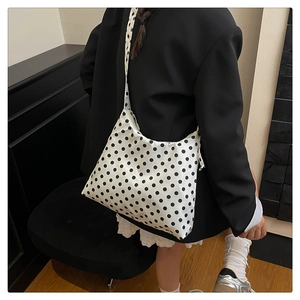 Detailed shoulder view of a black and white polka dot nylon tote bag on a model