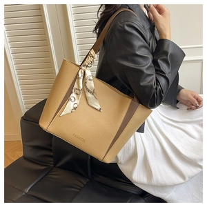 Gros plan d'un sac cabas en cuir kaki avec foulard en soie imprimé sur l'anse