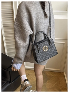 Detail of grey patterned crossbody bag with golden M logo and jacquard texture