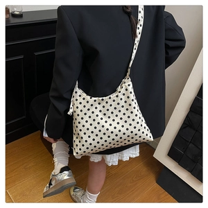 Detail view of a white polka dot hobo bag with wide shoulder strap and zipper closure