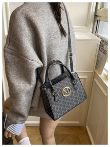 Dettaglio di una borsa a tracolla monogramma con logo M dorato e tracolla regolabile