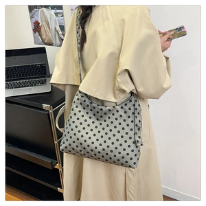 Detailed view of the spacious polka dot crescent bag worn with a stylish trench coat