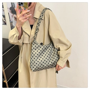 Sac hobo à pois vert olive porté par un mannequin en trench-coat pour un look mode