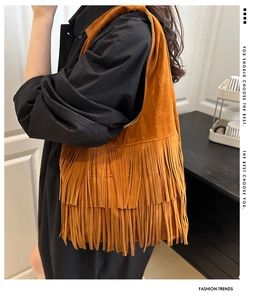 Dettaglio della borsa a tracolla bohémien arancio-marrone con frange su un cappotto nero