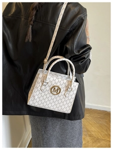 Detail of white handbag with all-over M letter print and golden magnetic buckle