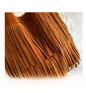 Detail view of brown faux suede tote bag featuring dense bohemian fringes and fine stitching