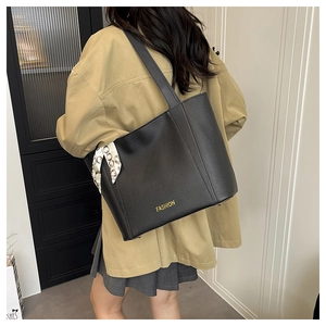 Détail du sac cabas en cuir grainé noir avec lettrage doré et foulard en soie décoratif